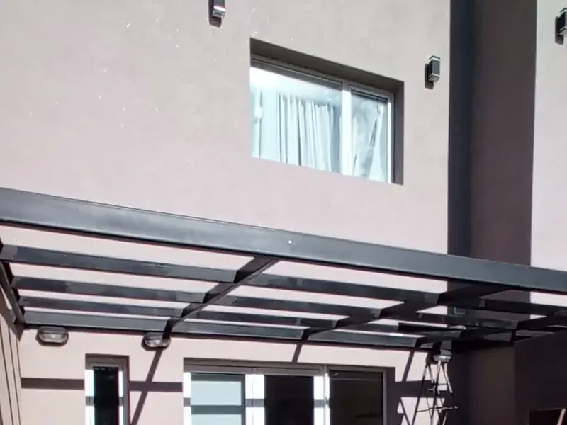 Pérgola metálica sobre el patio de una vivienda, con estructura negra y cubierta